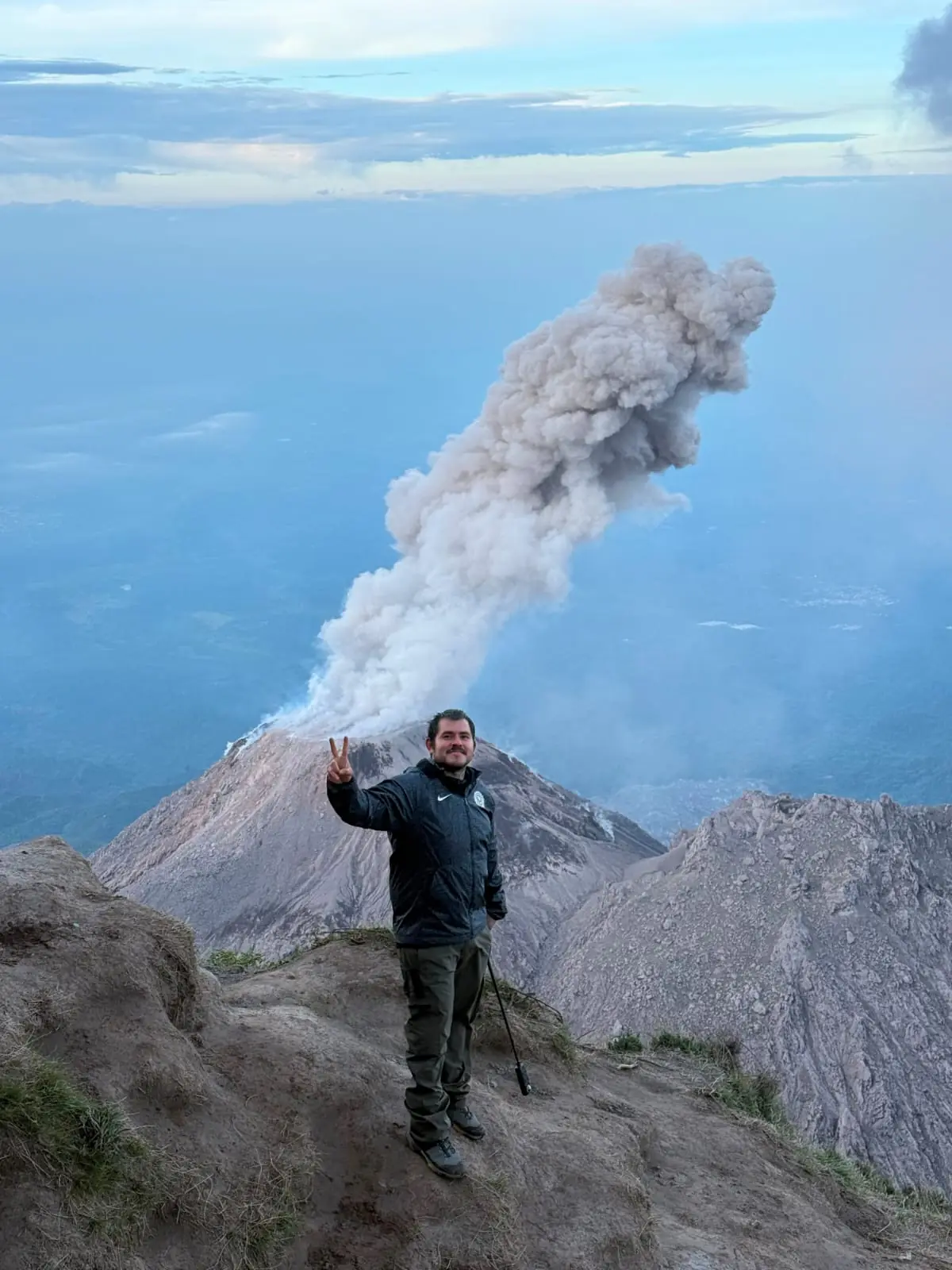 Excursionista en la cima junto a una fumarola volcánica