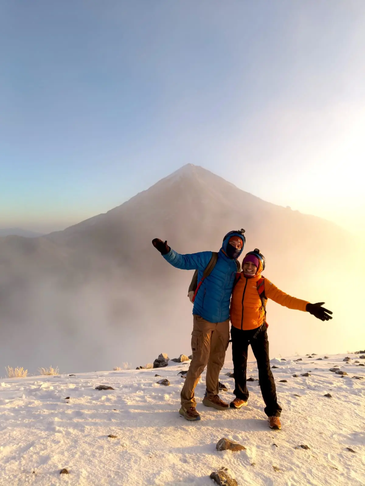 Pareja de excursionistas frente a un volcán nevado